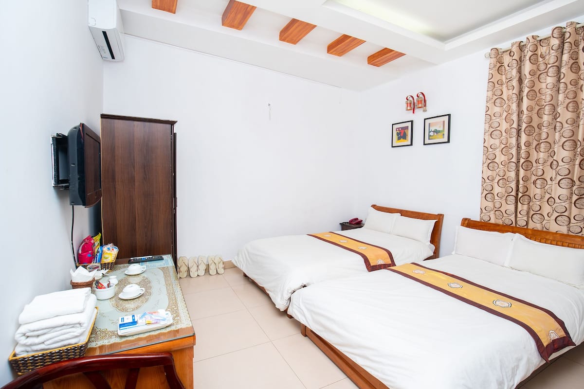 A hotel room with two beds, a desk with a telephone, and a television mounted on the wall.