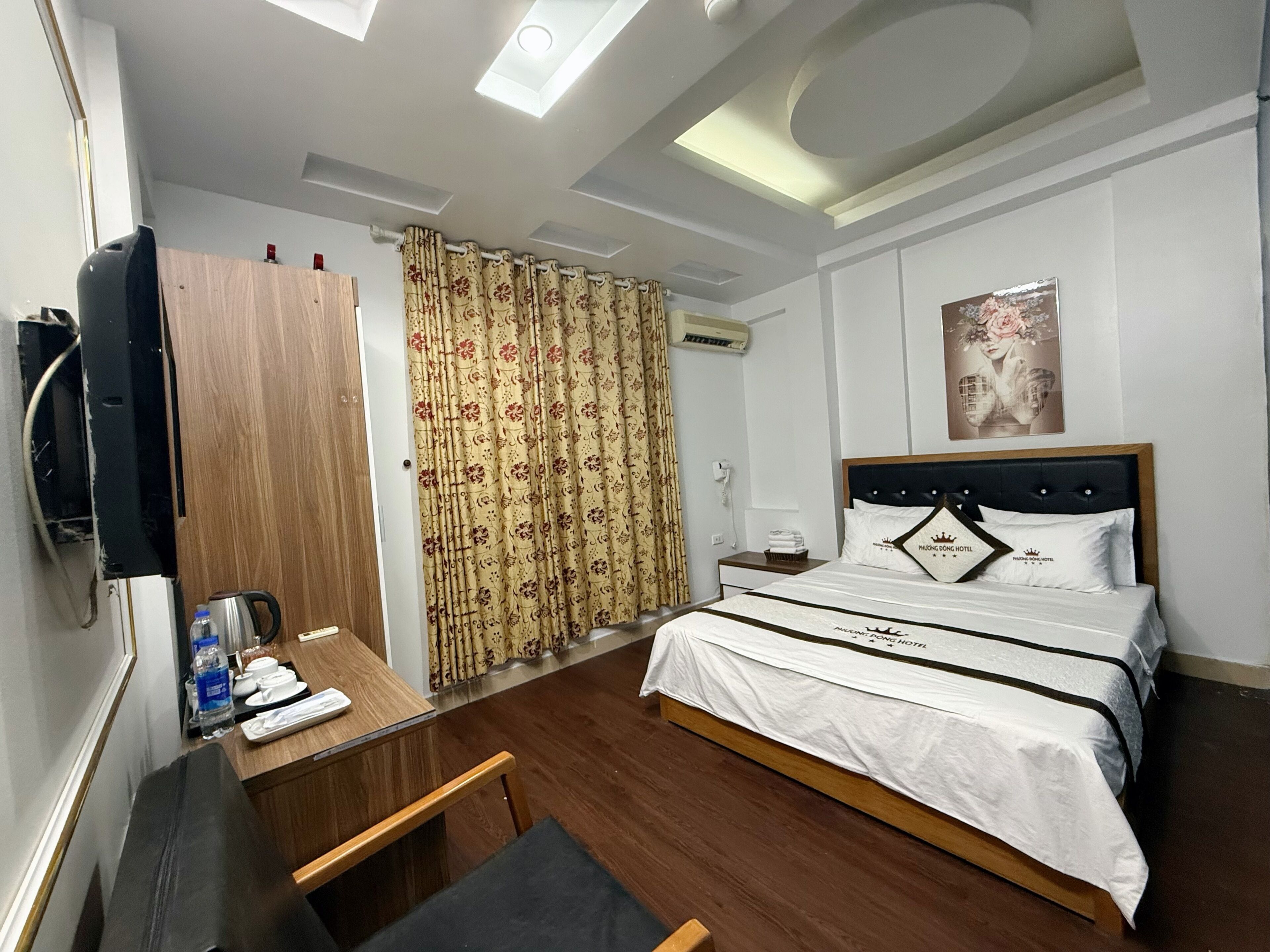 A hotel room with a bed, a desk with a chair, a wardrobe, and a shower area.