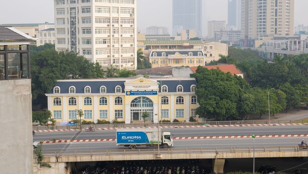 A multi-story building with a central entrance and a blue sign.