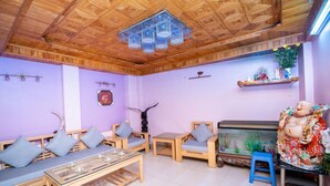 A room with wooden furniture, a glass coffee table, a fish tank, and a decorative statue.