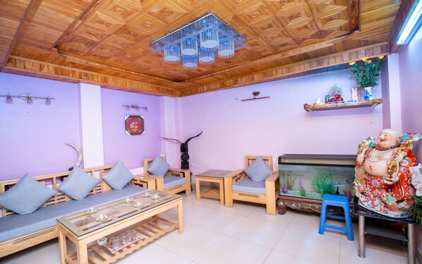 A room with wooden furniture, a glass coffee table, a fish tank, and a decorative statue.