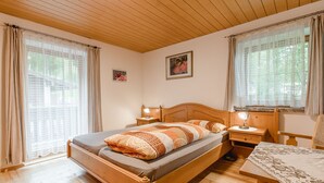 Un dormitorio acogedor con una cama de madera, una mesita de noche con lámpara y una mesa con mantel.