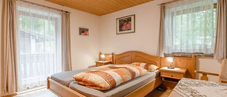 Un dormitorio acogedor con una cama de madera, una mesita de noche con lámpara y una mesa con mantel.