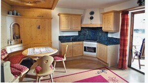 Una cocina compacta con armarios de madera, una estufa y un comedor con mesa y sillas.