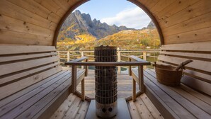 A wooden cabin with a circular window offering a view of mountains and autumn foliage. - Lofoten Apartments (Vagan)