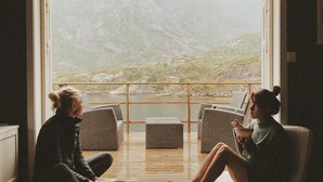 Two people sitting on a balcony with a view of a mountainous landscape. - Lofoten Apartments (Vagan)
