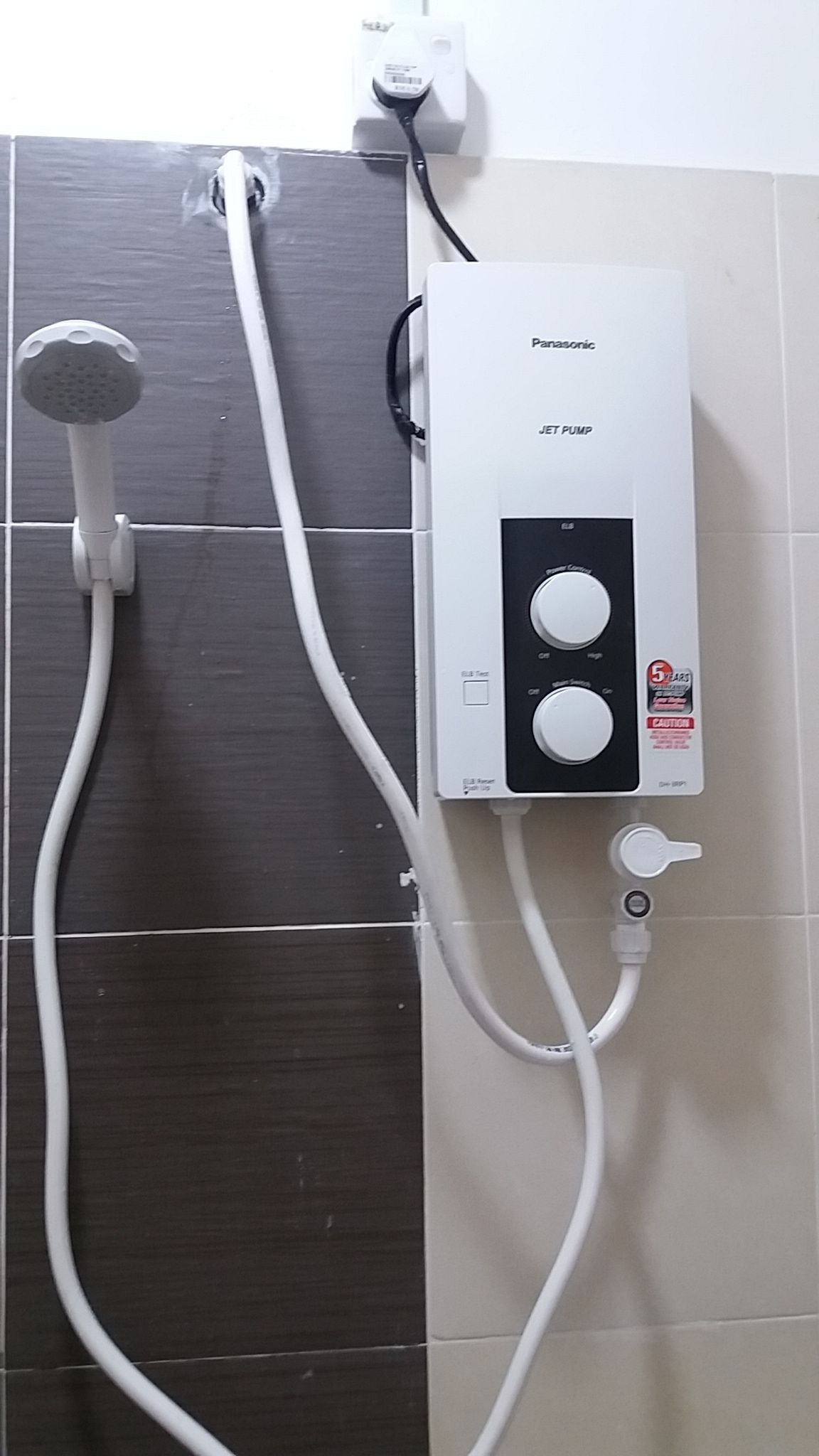 A Panasonic jet pump water heater with two control knobs, connected to a showerhead and a wall-mounted control panel.