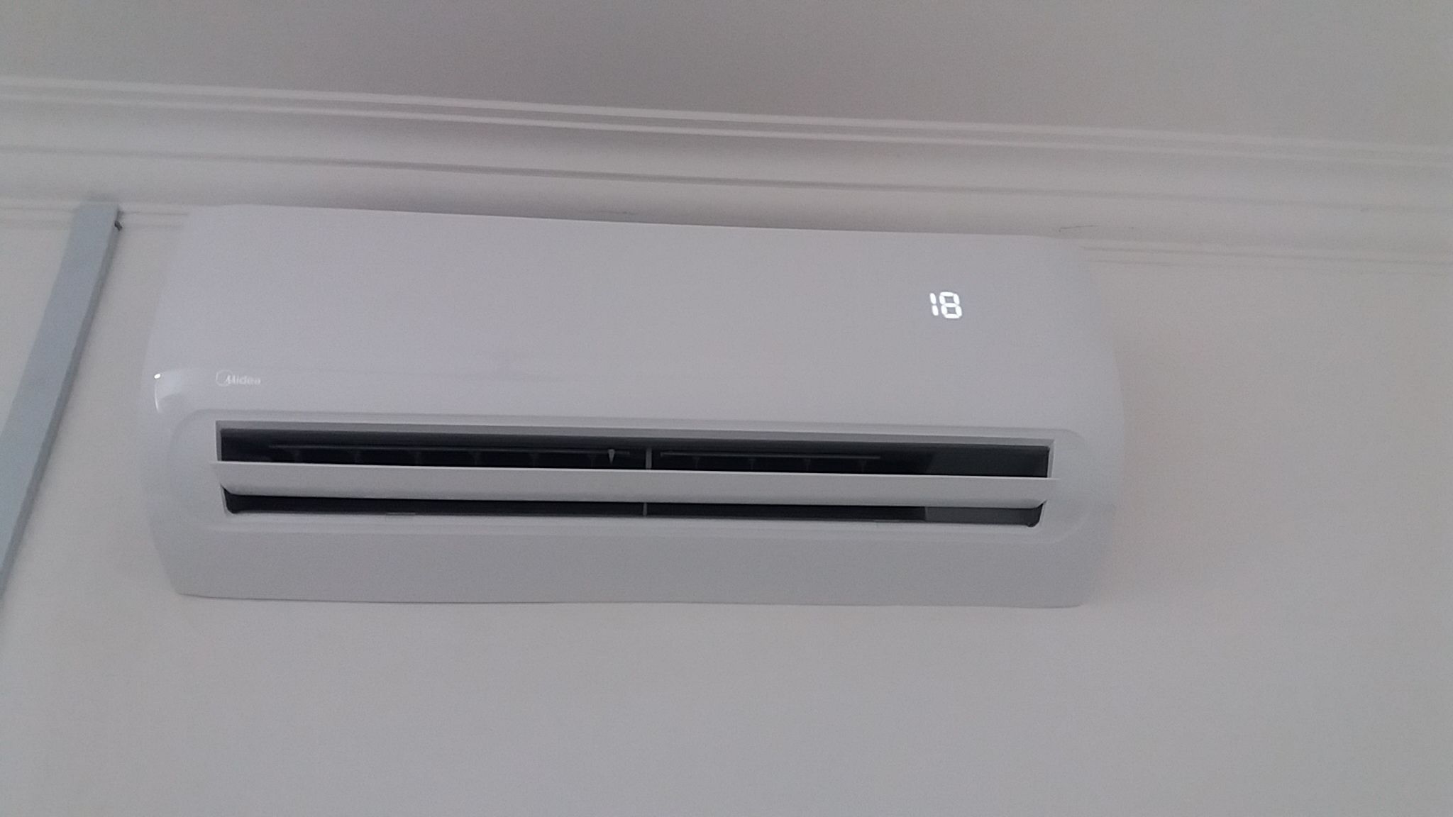 A white wall-mounted air conditioner with a digital display showing the temperature.