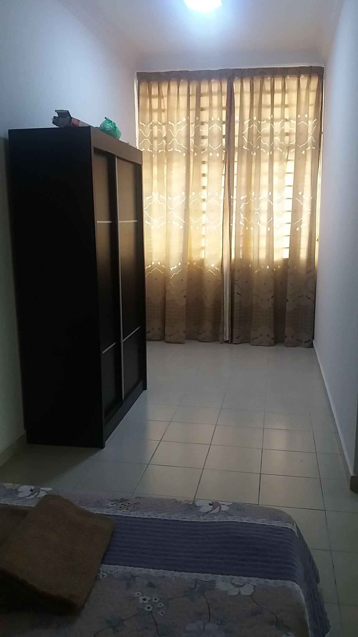 Una habitación con cama, armario y ventana con cortinas estampadas.