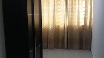 Una habitación con cama, armario y ventana con cortinas estampadas.