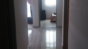 A hallway with a tiled floor, a rug, and a door leading to a room with a bed. - Kasa Heights Homestay (Alor Gajah)