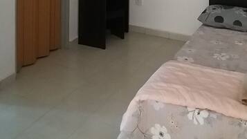 Un dormitorio con cama, armario, escritorio con espejo y ventilador de techo.