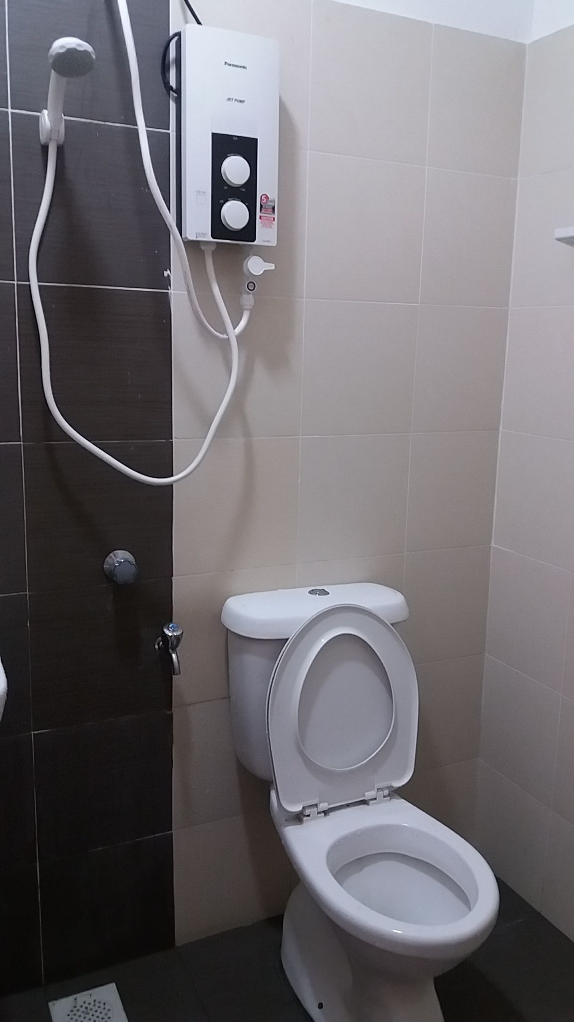 Une salle de bain équipée de toilettes, d’une douche et d ’un panneau de commande fixé au mur.