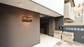 A hotel entrance with a sign reading "Avanzare." There are two trash bins and a wall-mounted sign with Japanese text. - MT House Bentencho (Osaka)