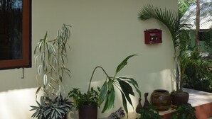 Un edificio con un letrero que dice "Manora Garden" y varias plantas en macetas alrededor de la entrada.