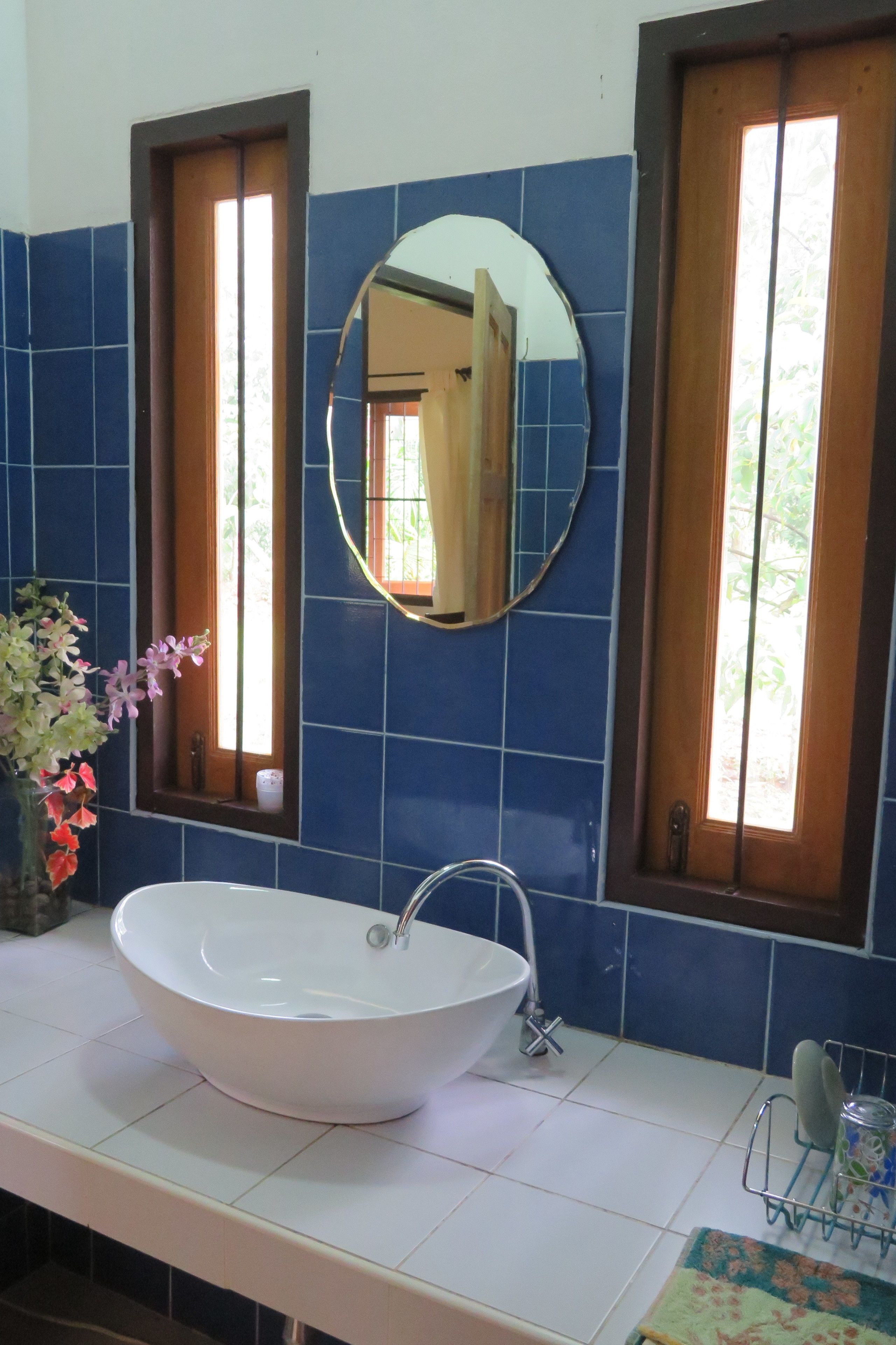 A bathroom with a white sink, a mirror, and blue tiles.