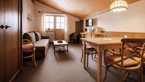 Uma sala de estar acolhedora com sofá, mesa de centro e mesa de jantar com cadeiras.
