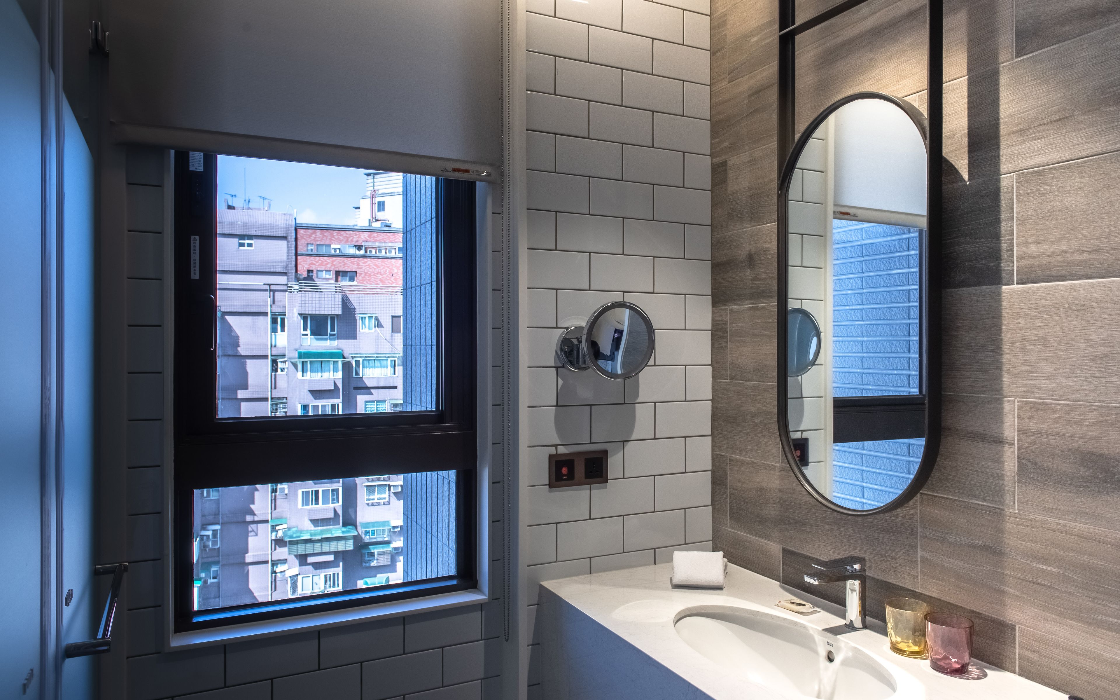 Ein modernes Badezimmer mit großem Fenster, Waschbecken und Spiegel.