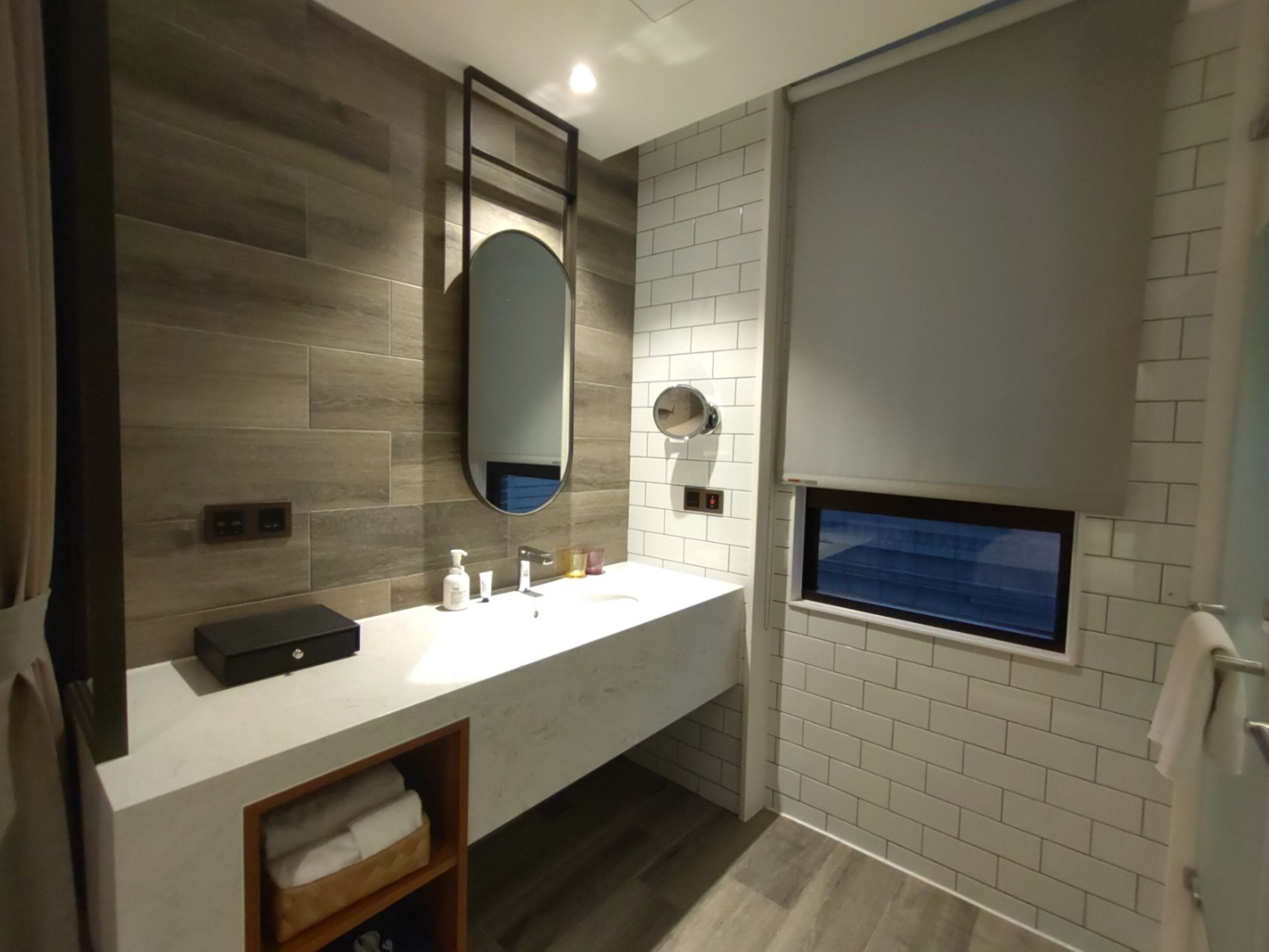 Un baño moderno con tocador de madera, un espejo grande y una ventana.