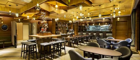 A modern bar area with wooden ceiling, multiple hanging light fixtures, and bar stools.