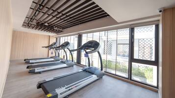 A gym with treadmills, a ceiling with exposed beams, and large windows offering a view of the outside.