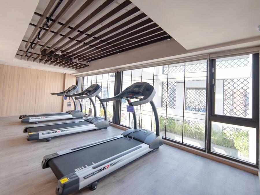 A gym with treadmills, a ceiling with exposed beams, and large windows offering a view of the outside.