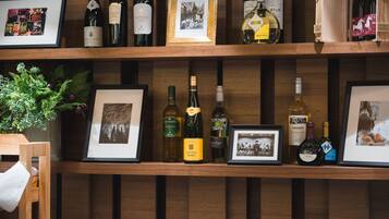 A wooden shelf with various wine bottles and framed pictures.