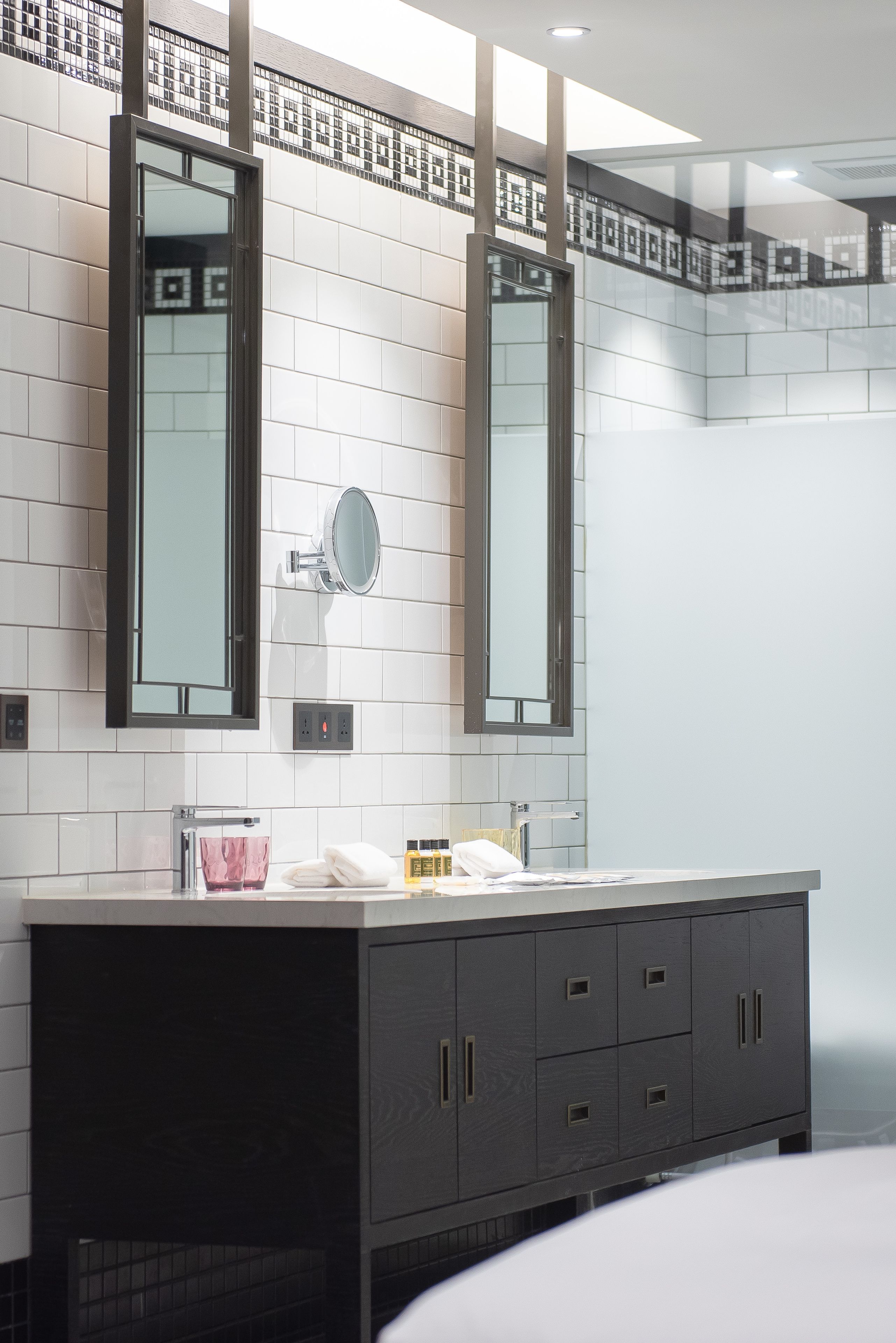 A modern bathroom with a large vanity, two mirrors, and a tiled backsplash.