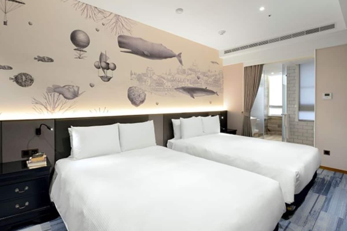 A hotel room with two beds, a nightstand, and a wall mural depicting marine life.
