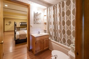 Ein Badezimmer mit einem Holzkosmetikschrank, einer Toilette und einer Dusche mit gemusterten Vorhängen.