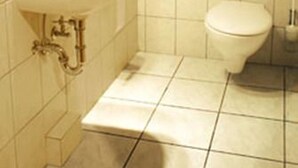 A small, tiled bathroom with a sink, toilet, and a mirror. - Heide Hotel Klütz (Burgwedel)