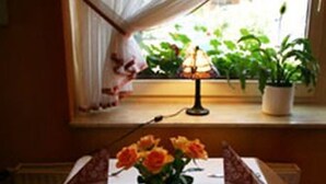 A dining table set with a white tablecloth, a vase of orange flowers, and folded napkins. - Heide Hotel Klütz (Burgwedel)