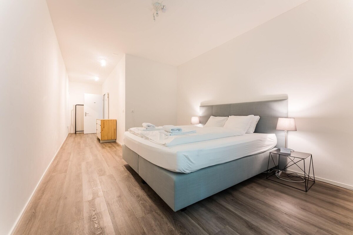 Un dormitorio moderno con cama, lámparas de noche y suelo de madera.