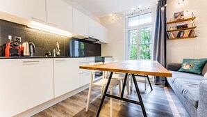 Una cocina moderna con armarios blancos, una mesa de comedor de madera y un horno empotrado.