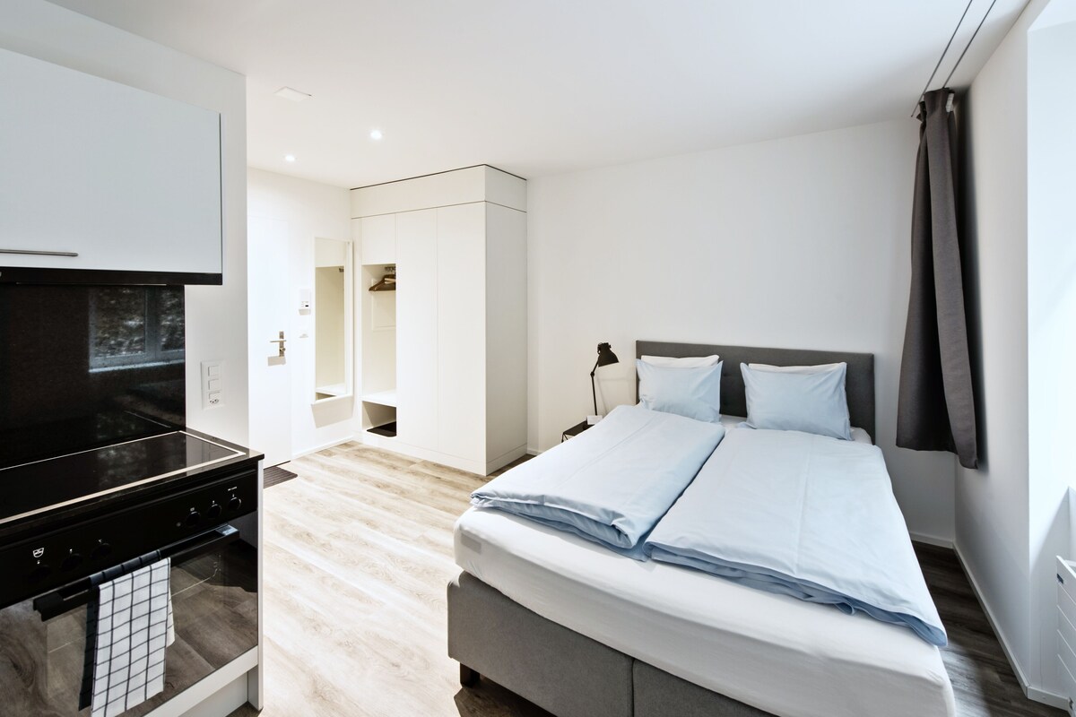 Une chambre d’hôtel moderne équipée d’un lit, d’un bureau et d’une kitchenette.