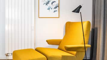 Ein modernes Wohnzimmer mit einem senffarbenen Sessel, einer schwarzen Stehlampe und einem gerahmten abstrakten Gemälde an der Wand.