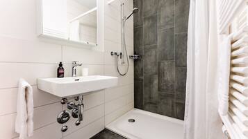 A modern bathroom with a white sink, mirror, and shower.