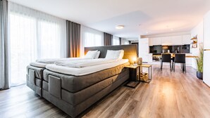 Una habitación de hotel moderna con una cama grande, una pequeña cocina y una mesa de comedor.