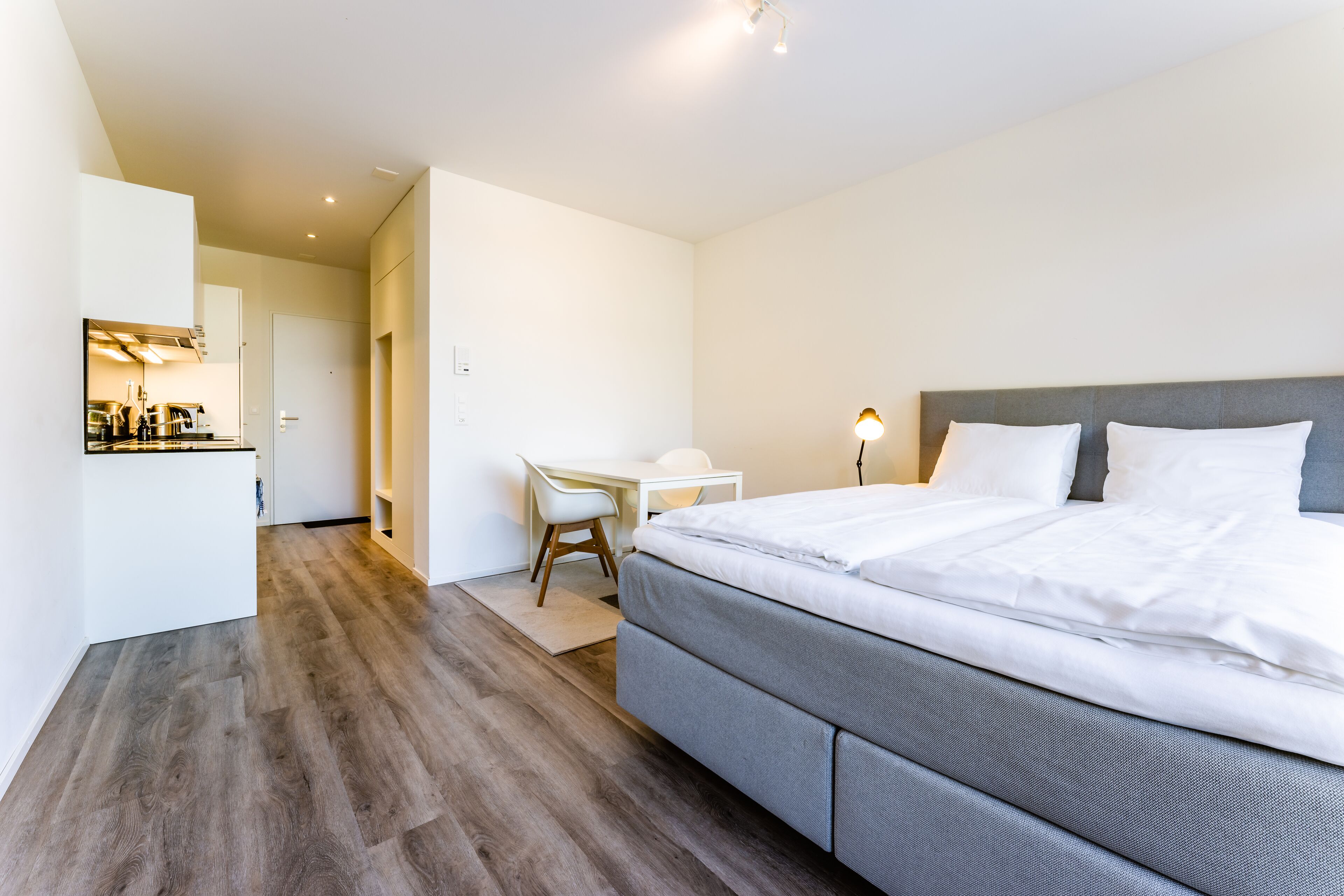 A modern hotel room with a large bed, a desk, and a chair.