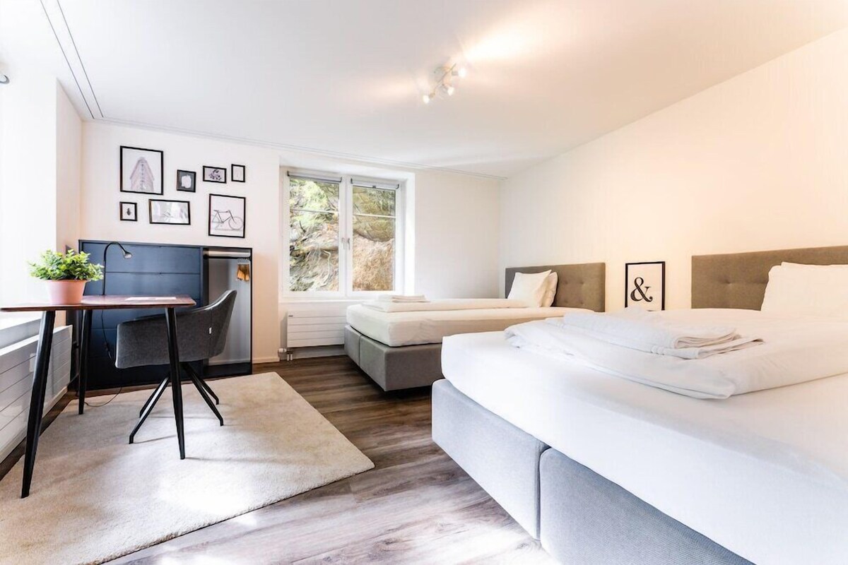 Une chambre d’hôtel moderne équipée d’un lit, d’un bureau, d’une chaise et offrant une vue sur l’extérieur.