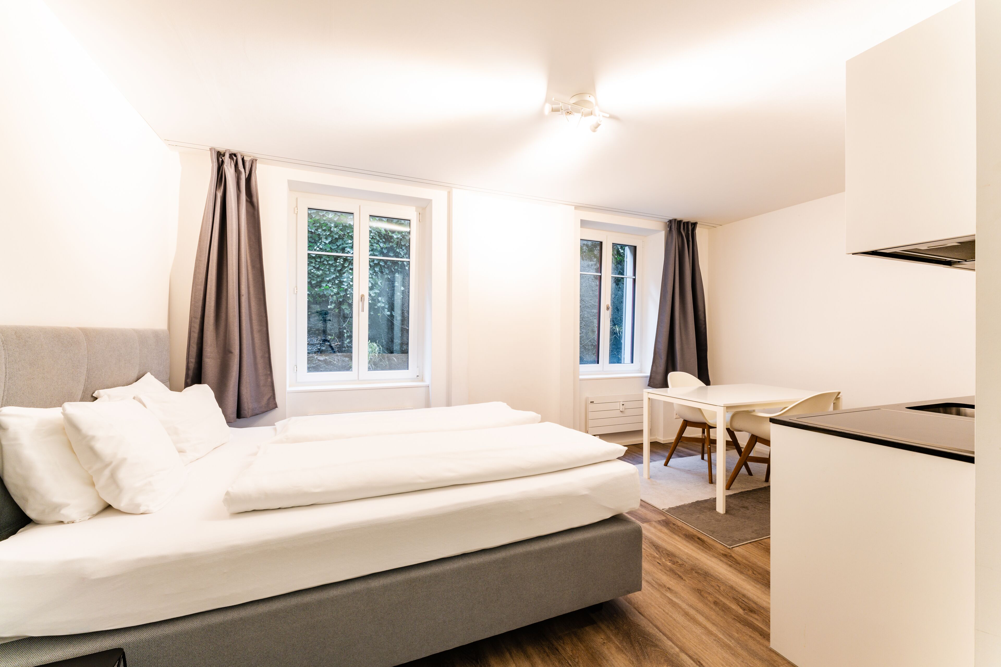 A modern bedroom with a bed, a desk, and a chair.