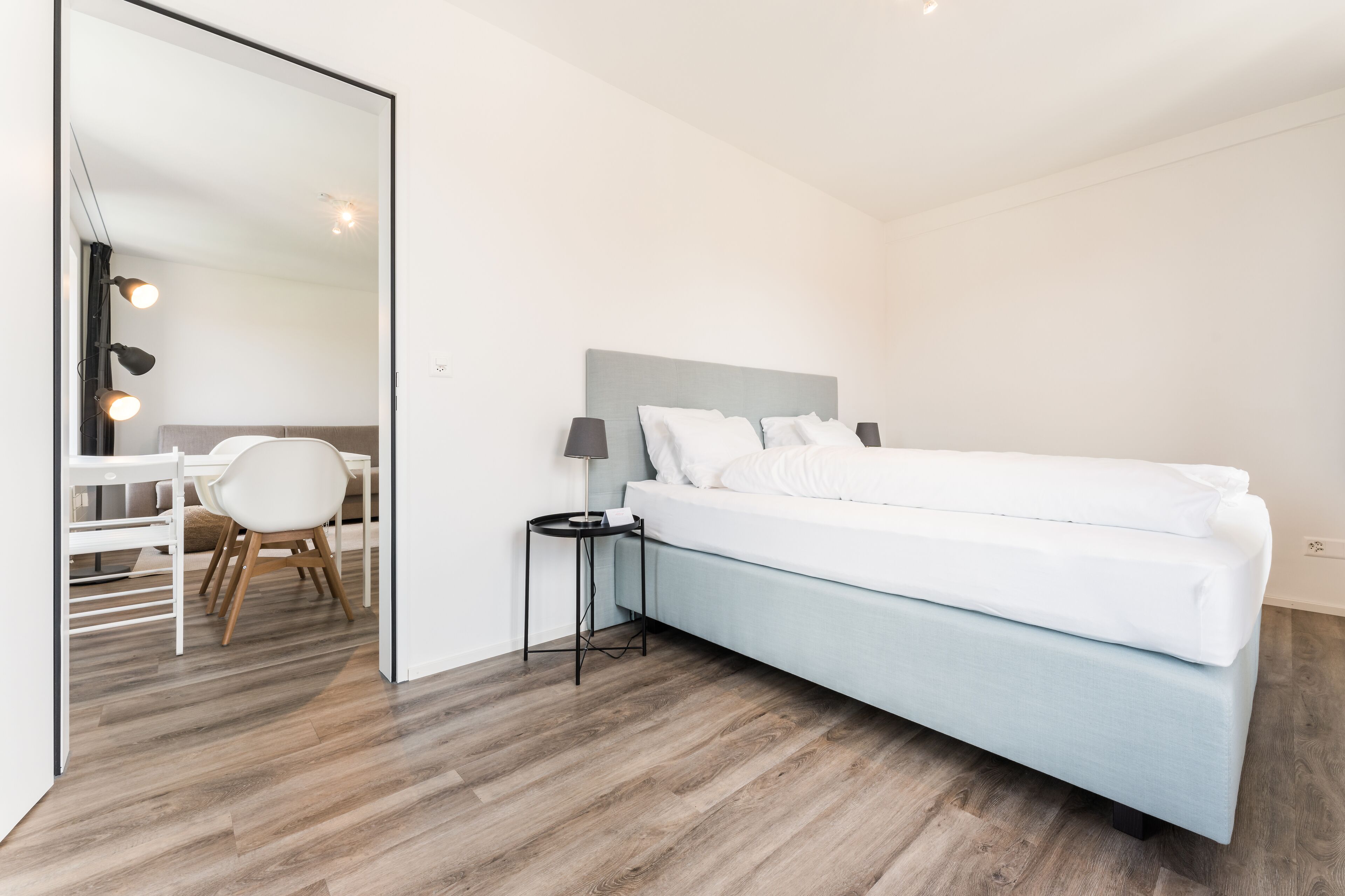 A modern bedroom with a bed, bedside table, and a chair.