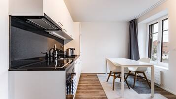 A modern kitchen with a black stove, white cabinets, and a dining area with a white table and chairs.