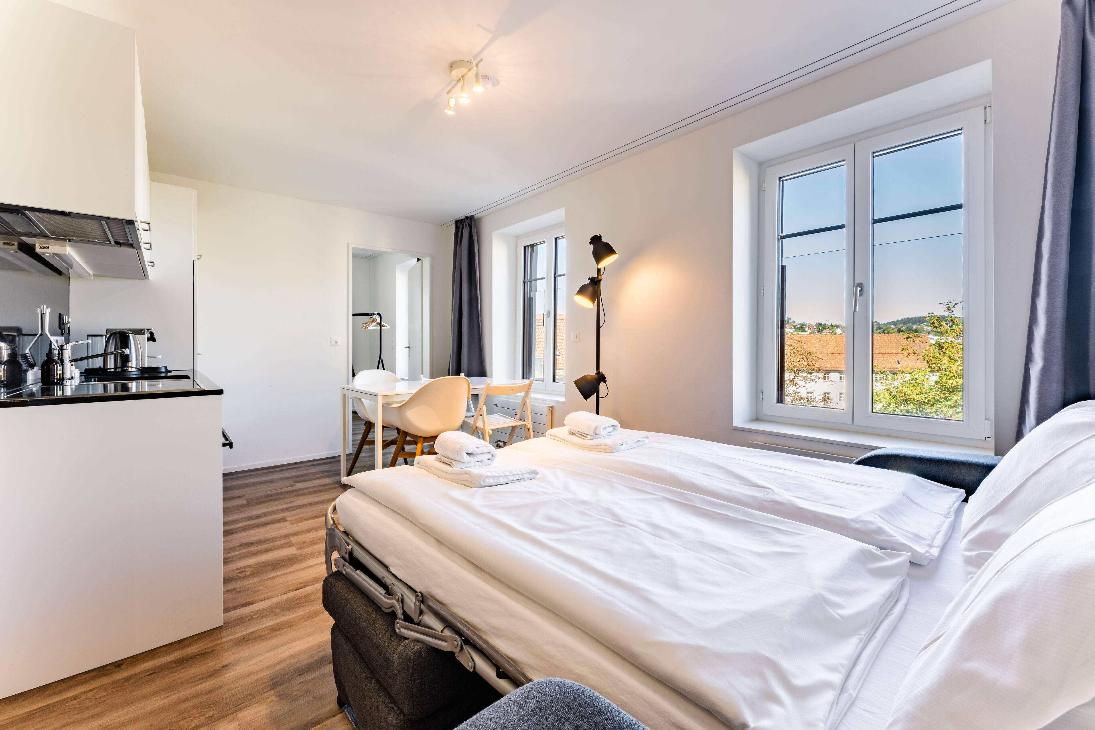 Een moderne hotelkamer met een bed, een bureau en een kitchenette.