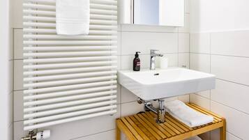 Ein modernes Badezimmer mit einem weißen Waschbecken, einem hölzernen Handtuchhalter und einem darauf liegenden Handtuch.