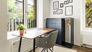 A modern room with a wooden table, a grey chair, a fireplace, and framed pictures on the wall.