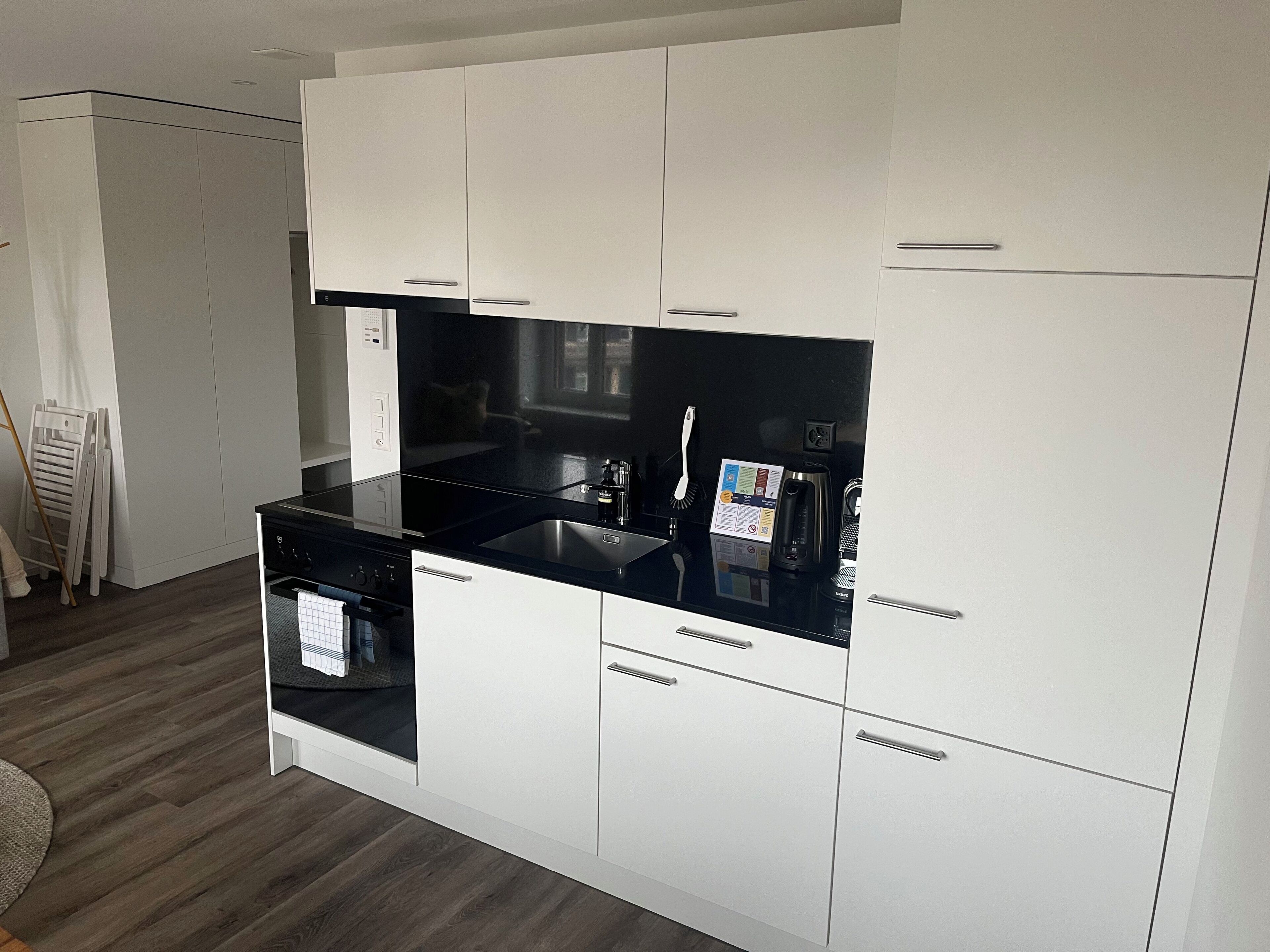 A modern kitchen with white cabinets, a black countertop, and stainless steel appliances.