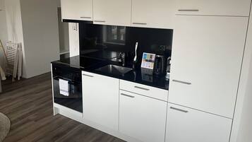 Een moderne keuken met witte kasten, een zwart aanrecht en roestvrijstalen apparatuur.