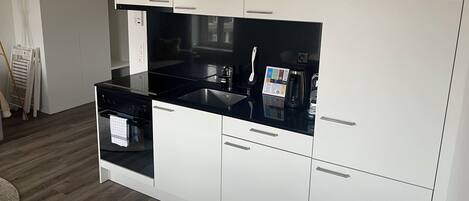 Una cocina moderna con armarios blancos, encimera negra y electrodomésticos de acero inoxidable.