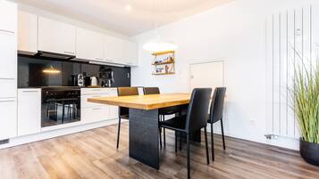A modern kitchen with white cabinetry, a wooden dining table, and black chairs.